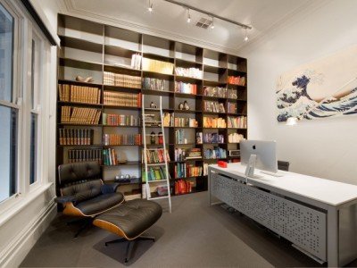 a room with a desk and shelves with books on it