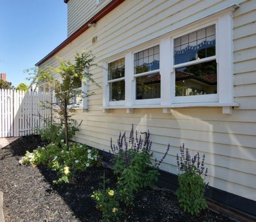 a house with a white fence and trees in front of it