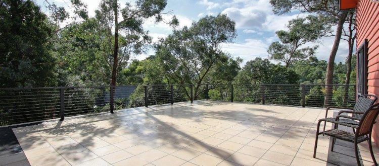Broad paved terrace overlooking a wooded garden