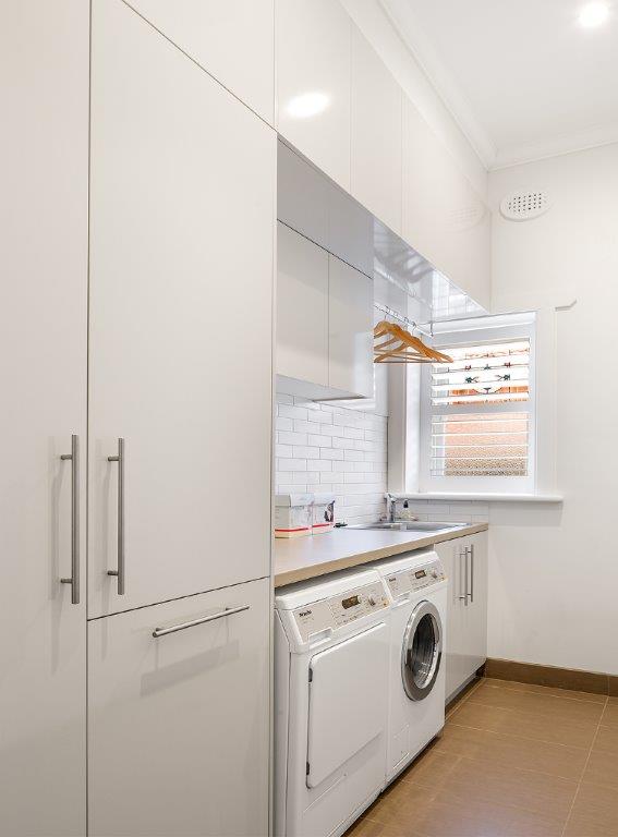 White laundry cabinetry and front-loading washing machine