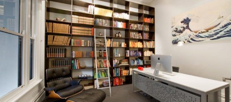 a room with a desk and shelves with books