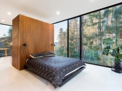 Bedroom with glass walls surrounded by forest