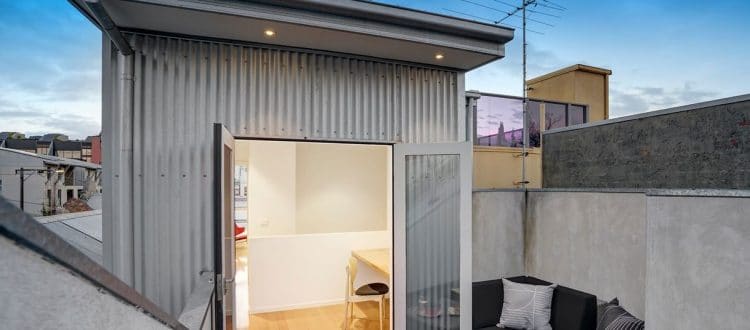 Metal-clad upper-level room opening onto a roof terrace