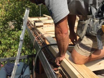 Builder working on timber framing at roof level