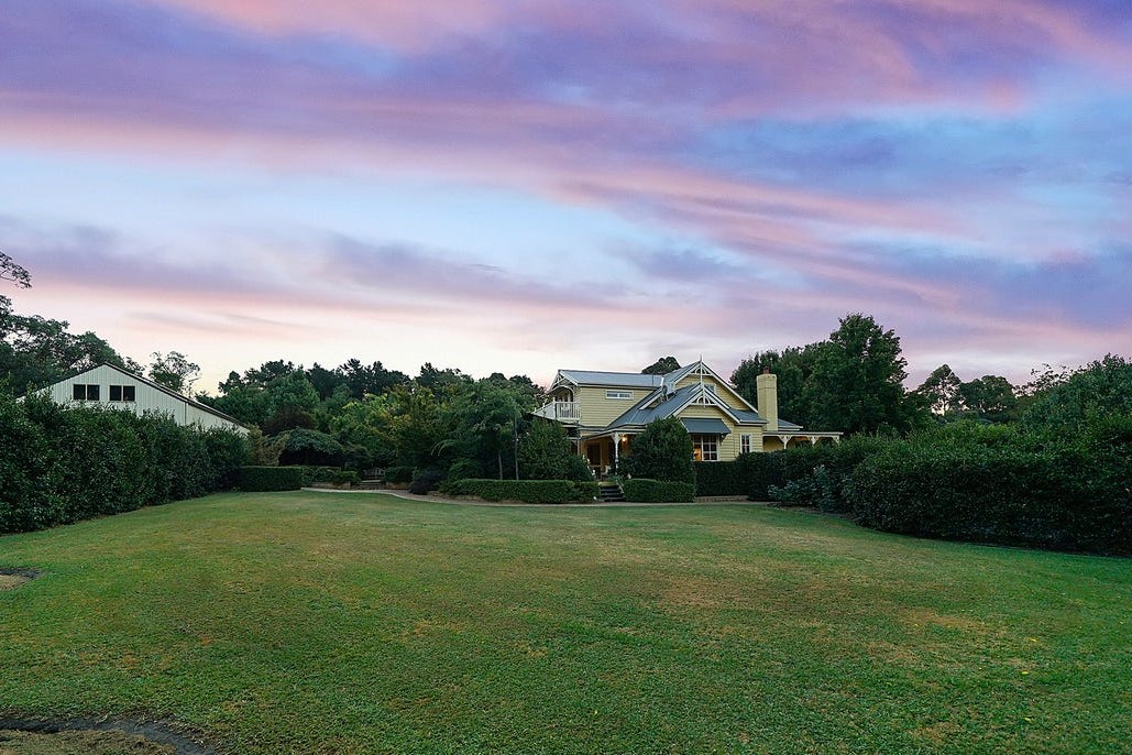 a house with a large lawn and trees in the front