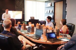 a group of people sitting around a table with laptops