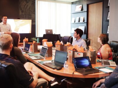 a group of people sitting around a table with laptops