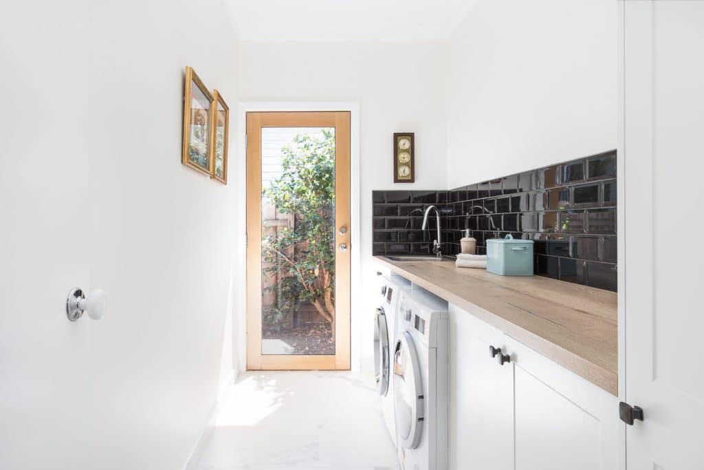 White laundry with a black tiled splashback and garden door