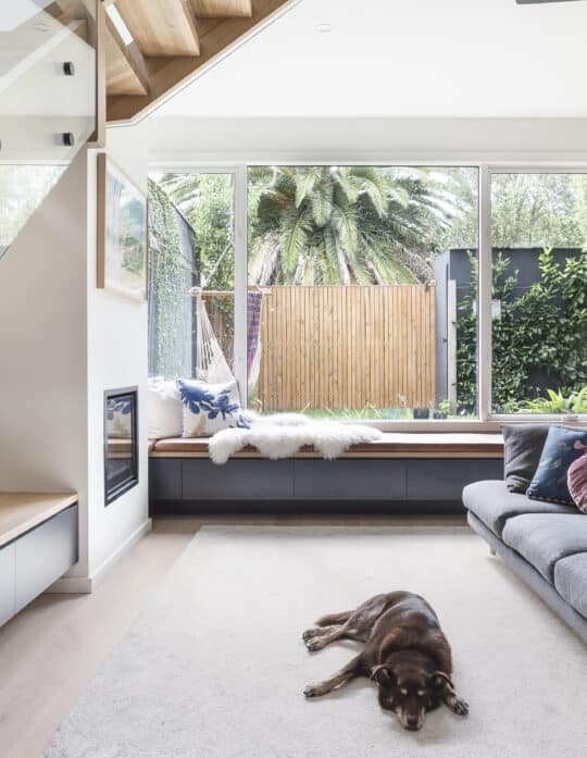 Living room with a grey sofa beside a glass stair balustrade