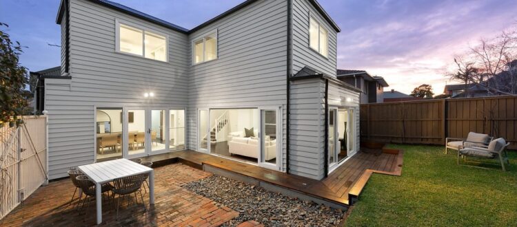 Angular two-storey rear addition beside a timber deck at dusk